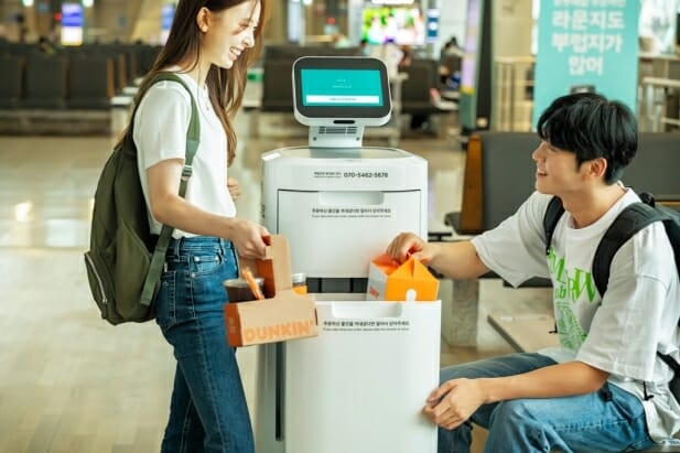 인천공항 이용객이 배달로봇 '에이딜리'가 배달해 주는 빵과 음료를 받고 있다. / 사진=우아한형제들